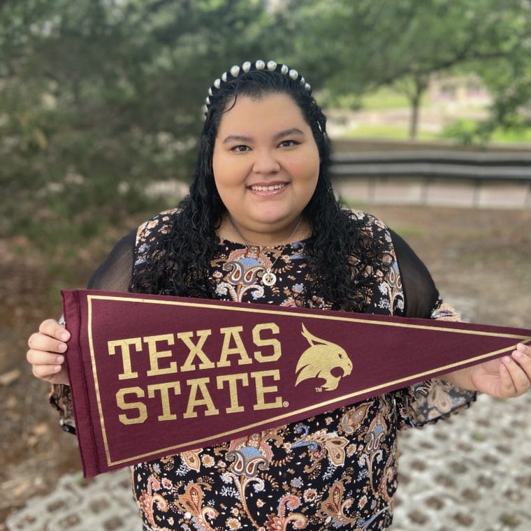 Serenity De Leon holding banner that reads Texas State