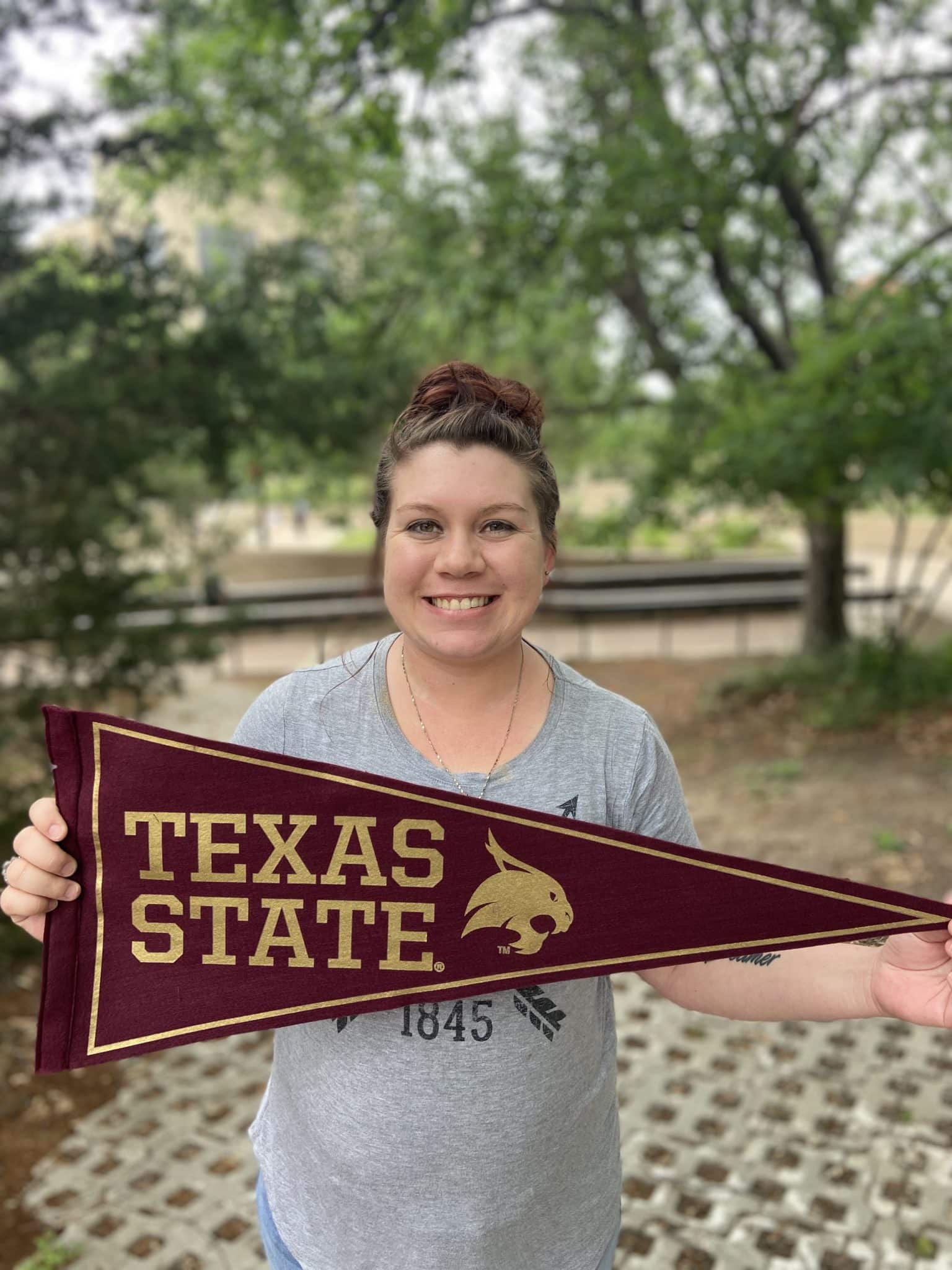 Johanna Foster holding maroon banner that reads Texas State